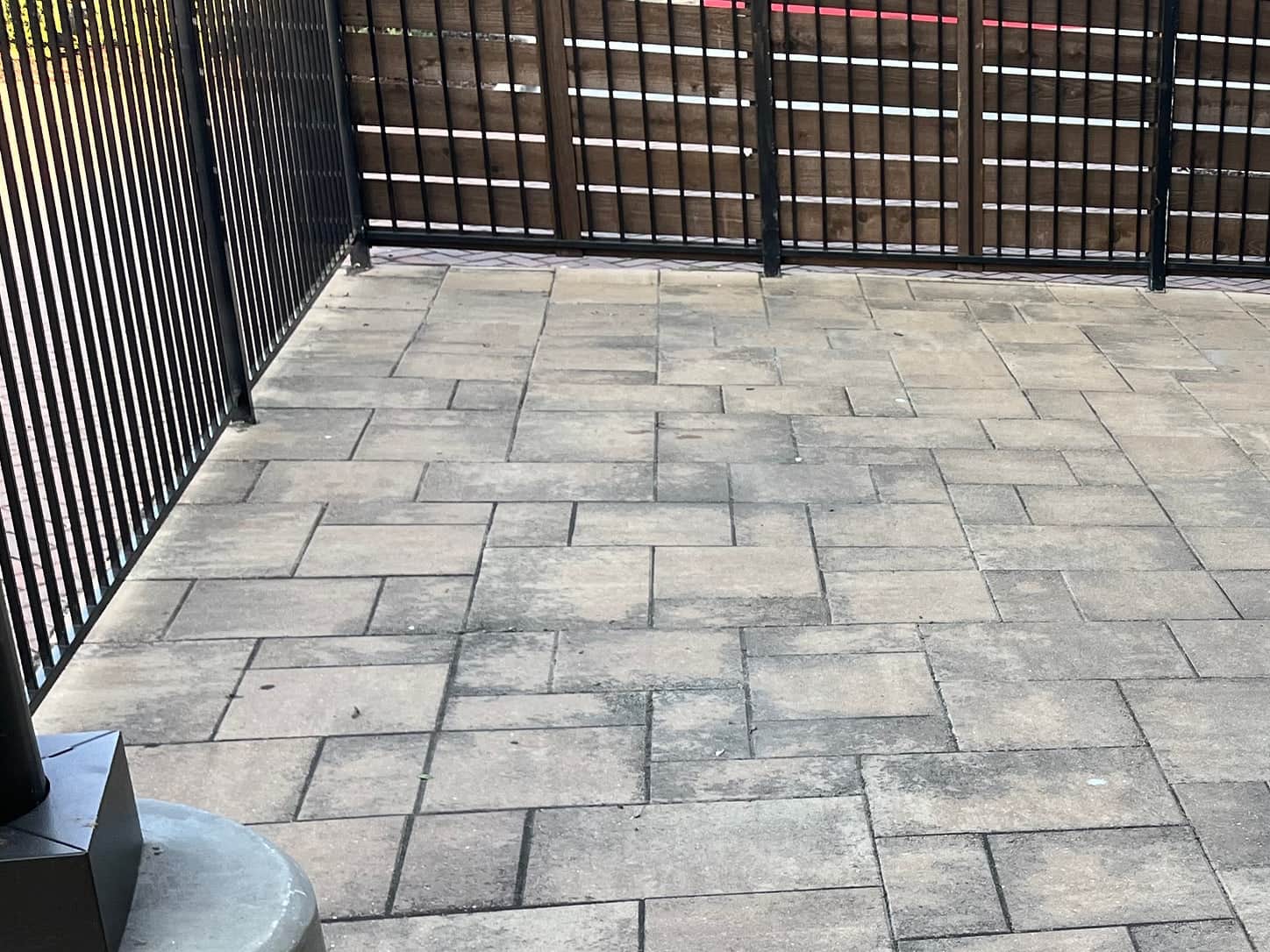 Restaurant patio laid in concrete pavers, uniformly grey with traffic film and weathering before cleaning.